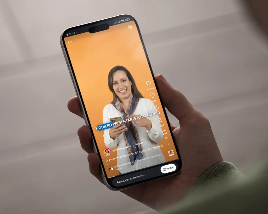 una fotografía de una mano sosteniendo un móvil iPhone, el cual muestra un video reel en la aplicación de Instagram, donde se ve un video de Carolina Corcho, con un agente de ia, con miles de reproducciones y reacciones.